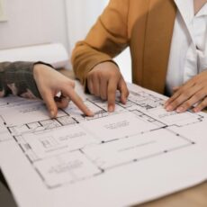 Two professionals discussing architectural plans in an office setting.